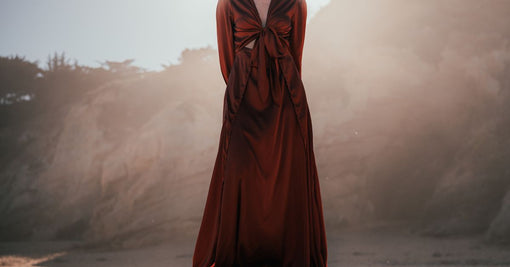 Woman in flowing silk dress standing on beach in natural sunlight — silk nightdress chemise nightgown guide Calliope Studio Australia