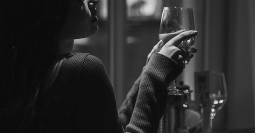Sophisticated woman in elegant dress enjoying wine at cafe — pure silk pyjamas australia 100 percent mulberry Calliope Studio