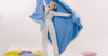 Woman in silk sleepwear holding soft blanket in bedroom — silk pillowcase vs silk pyjamas where to start Calliope Studio Australia